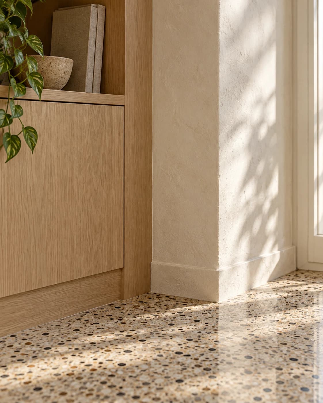 Materialanschluss zwischen Terrazzoboden, hellem Eichenholz und verputzter Wand