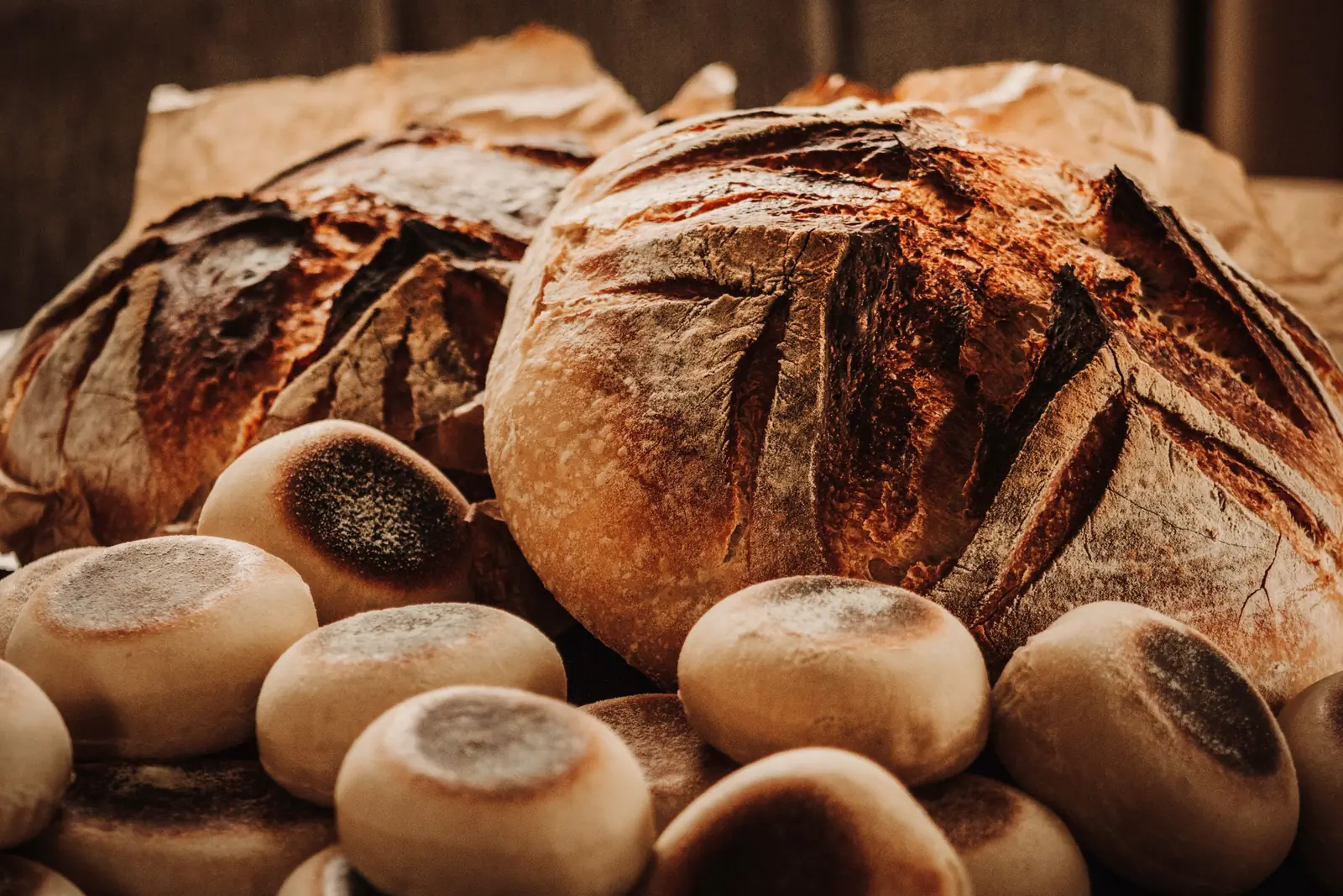 Frisch gebackene Sauerteigbrote und Brötchen auf Holz